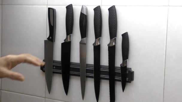 男の手は、磁気ストライプ上のナイフのセットから目的のアイテムを選択します。台所のナイフのセット. - 映像、動画