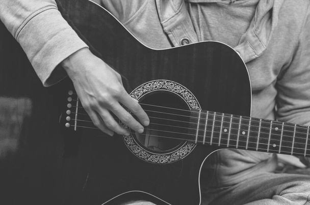 Černobílá fotka hudebníka hrajícího na kytaru. Prsty se dotýkají strun zblízka - Fotografie, Obrázek