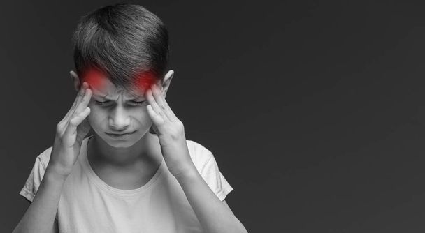 Pohledný teenager chlapec v ležérní bílé tričko stojí nad izolovaným pozadím trpí bolestí hlavy zoufalý a ve stresu, protože bolest a migréna. Ruce za hlavu - Fotografie, Obrázek