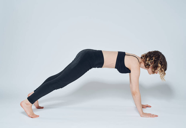 Žena dělá cvičení pro rovnoměrné držení těla na lehkém pozadí v plném růstu - Fotografie, Obrázek