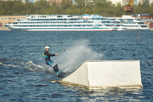Facet jeździ na desce na rzece. Sporty aktywne i ekstremalne - Zdjęcie, obraz