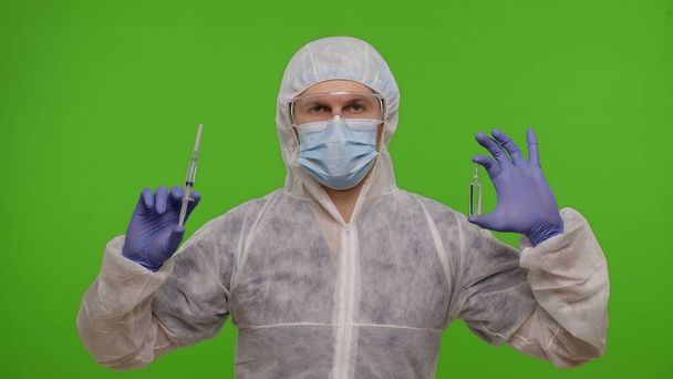 Aşı ampullü PPE giysisi giyen doktor ellerinde Coronavirus 'a karşı aşı öneriyor. - Fotoğraf, Görsel