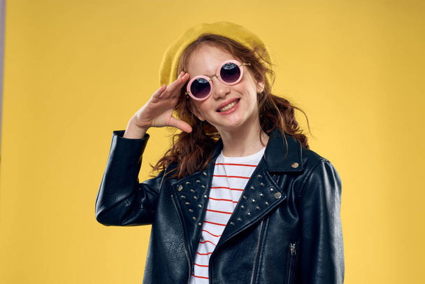 Fröhliches kleines Mädchen mit Sonnenbrille und Hut Lifestyle-Studio gelben Hintergrund Mode - Foto, Bild