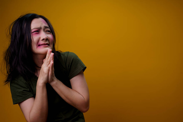 Femme asiatique avec des ecchymoses sur le visage victime de violence, isolée sur le fond. - Photo, image
