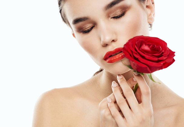 Mujer con los ojos cerrados Maquillaje en la cara y flor roja hombros desnudos - Foto, imagen