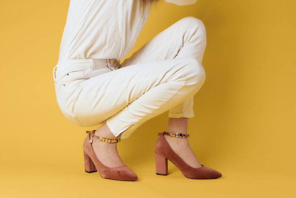 Female legs white pants fashionable clothes shoes luxury yellow background - Foto, Bild