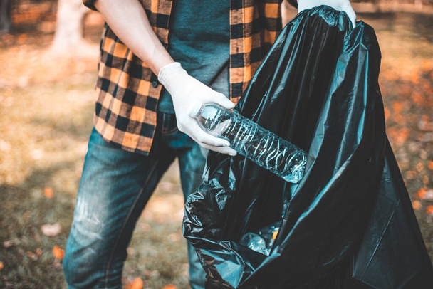 Les hommes bénévoles portent des bouteilles d'eau ou des sacs en plastique qui sont tombés dans le parc les mettre dans des poubelles, Protection de l'environnement ou bénévolat pour la charité, Élimination des déchets par le recyclage. - Photo, image