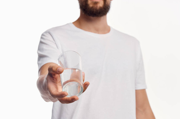 a glass of clean water in the hand of a man in a light shirt cropped view - Photo, image