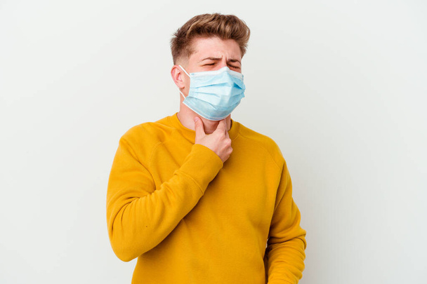 白い背景に隔離されたコロナウイルスのためのマスクを身に着けている若い男は、ウイルスや感染症のために喉の痛みを受ける. - 写真・画像