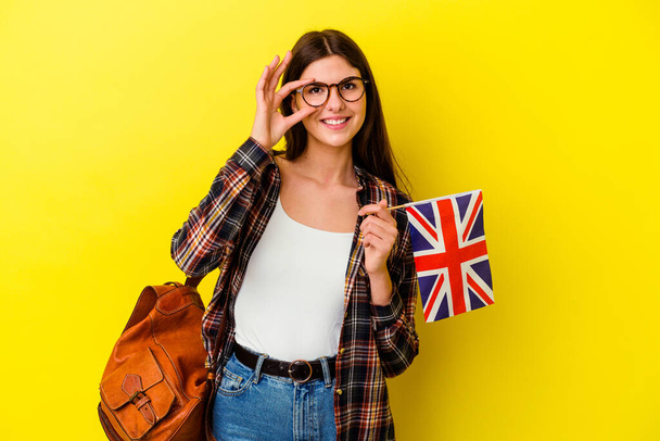 Mladá žena studuje angličtinu izolované na růžovém pozadí vzrušený vedení ok gesto na oku. - Fotografie, Obrázek
