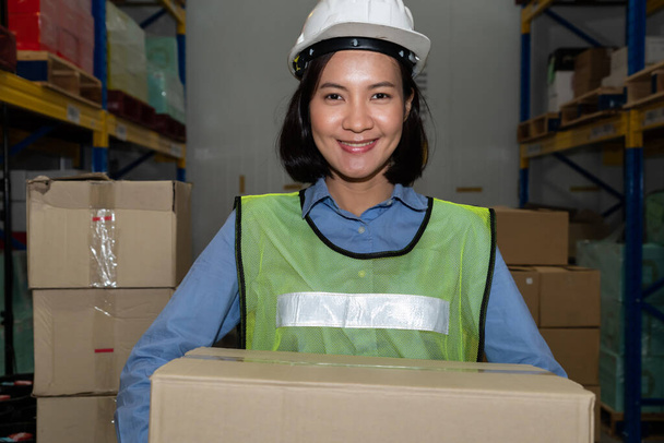 Retrato de una joven mujer asiática trabajadora de almacén sonriendo en el almacén - Foto, imagen