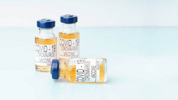 Trzy fiolki szczepionki Covid-19 na niebieskim stole. przestrzeń kopiowania - Zdjęcie, obraz