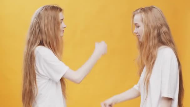 Secret hand greeting. Young redhead twin sisters making fist bump and explosion, looking at each other - Footage, Video