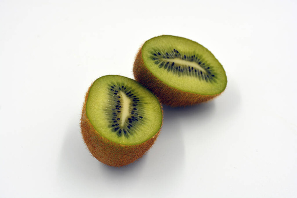 Frutos saudáveis maduros deliciosos para a saúde humana. Frutas kiwi verdes dispostas sobre um fundo branco. Um quivi inteiro é cortado em dois pedaços pares.  - Foto, Imagem