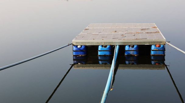 水の上の太陽電池パネル。汚れた太陽電池パネルは、水の背景に家や小さな農場で水を汲み上げるために電気を発生させるために池の中に水を浮かべ、コピースペースで影。選択的焦点 - 写真・画像