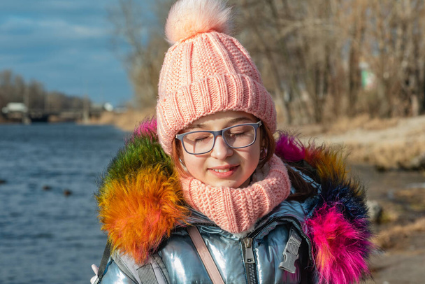 Portrait of young beautiful girl in winter style. Girl in glasses and a pink hat in winter. River - Photo, Image