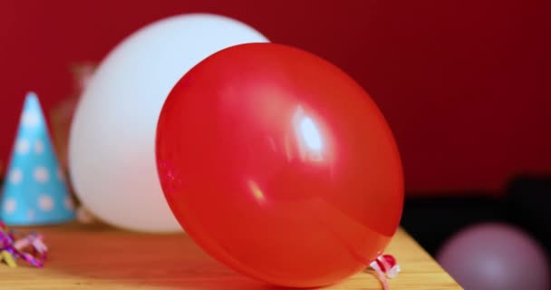 Mujer joven con lápiz labial rojo frotado y gorra, sentada cansada en la mesa en la habitación desordenada después de la fiesta de cumpleaños - Metraje, vídeo