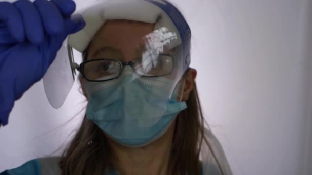 Γυναικείο ιατρικό προσωπικό που αφαιρεί την ασπίδα προσώπου μετά τη βάρδια  - Πλάνα, βίντεο