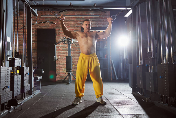 Professioneller Bodybuilder macht seine Fitnessstudio-Routine drinnen - Foto, Bild