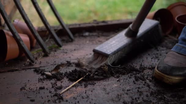 Zahradník zametá dřevěnou chatu pokrytou hlínou a nečistotami - Záběry, video