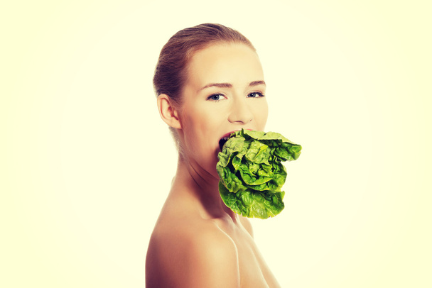 Woman with lettuce in mouth. - Φωτογραφία, εικόνα