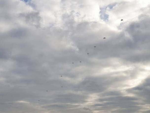 Sotilaallinen laskuvarjohyppääminen, taivaalla hyppäävät hyppääjät bledowskan aavikolla Puolassa  - Valokuva, kuva