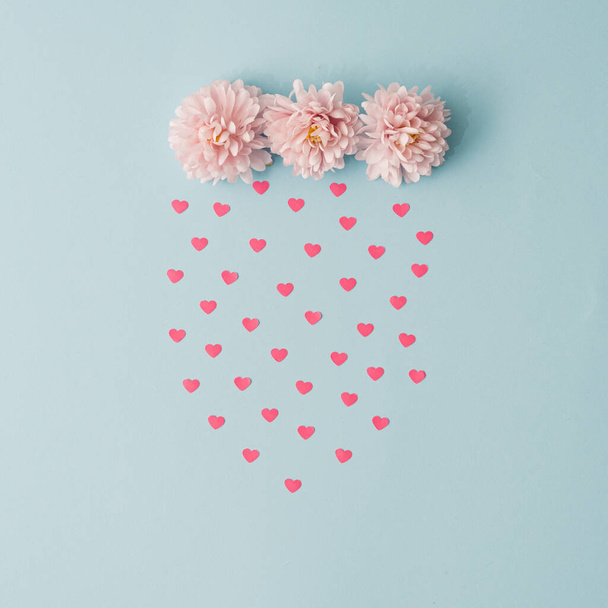 Пастель рожеві квіти і дощ, зроблений з сердець. Валентинки або жіноча концепція дня. Мінімальна естетика. - Фото, зображення