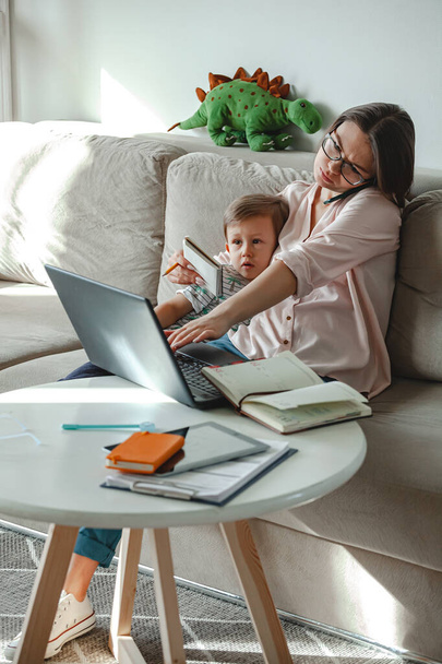 Concept of work at home and home family education, mother working with laptop at home, child playing nearby - Photo, Image