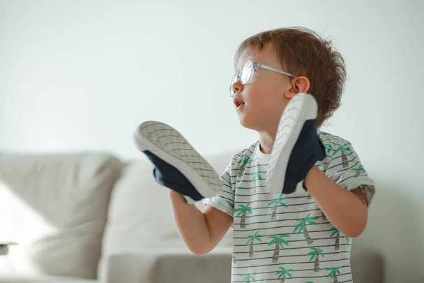Niño con autismo en gafas juega con sus zapatos - Foto, imagen
