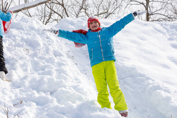 Šťastná dívka stojí na svahu skluzavky v zimě a vrhá ruce nahoru raduje se z prvního sněhu - Fotografie, Obrázek