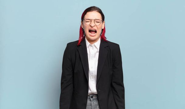 young attractive red hair woman shouting aggressively, looking very angry, frustrated, outraged or annoyed, screaming no - Photo, image