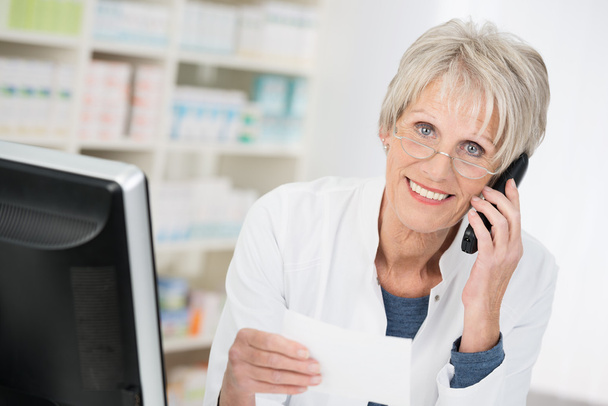 Smiling pharmacist checking up on a prescription - Foto, Bild