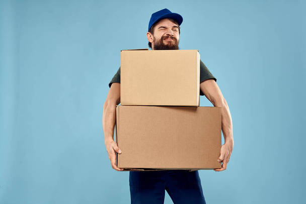 muž s krabicemi služby dodací uniforma pracovní modré pozadí - Fotografie, Obrázek
