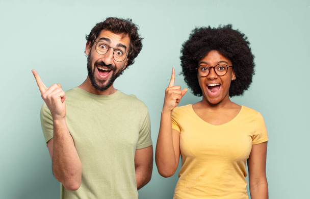 multiracial couple of friends feeling like a happy and excited genius after realizing an idea, cheerfully raising finger, eureka! - Foto, Imagen
