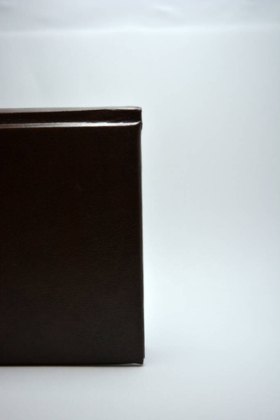 Egy kis könyv, egy jegyzetfüzet, egy napló egy sötét barna borító található egy fehér háttér érdekes világítás. - Fotó, kép