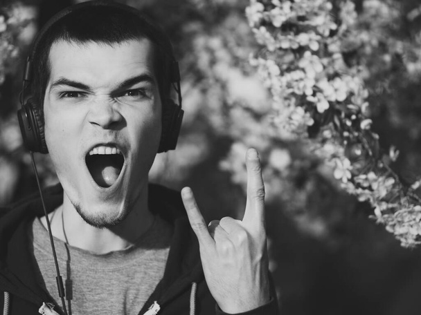 Rock i heavy metal. Młody człowiek krzyczy i pokazuje symbol skały - Zdjęcie, obraz