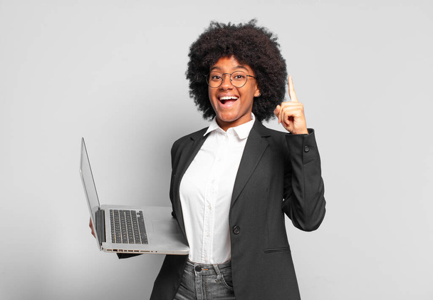 young afro businesswoman feeling like a happy and excited genius after realizing an idea, cheerfully raising finger, eureka!. business concept - Foto, Imagen