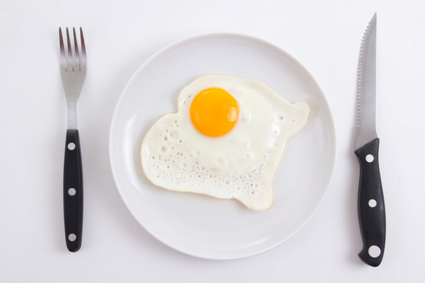 жареные яйца в тарелку с вилкой и ножом над белой - Фото, изображение