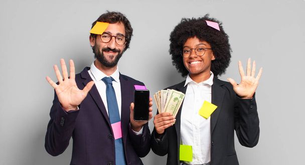 young businesspeople smiling and looking friendly, showing number five or fifth with hand forward, counting down. humorous business concept - Foto, immagini