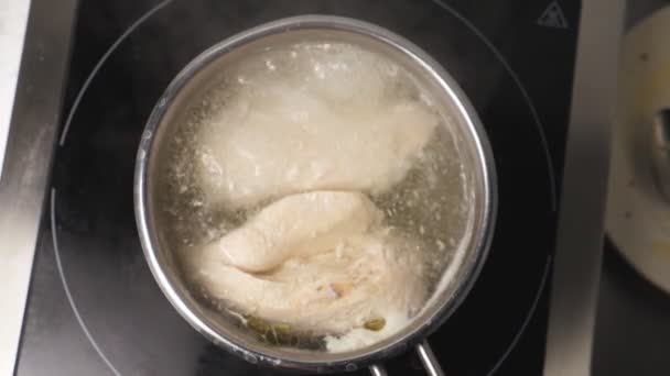 View of chicken breasts are boiling in a metal saucepan at kitchen restaurant. Chicken fillet is cooking in stewpan at cuisine. Concept of preparing meat. Top view Slow motion - Footage, Video