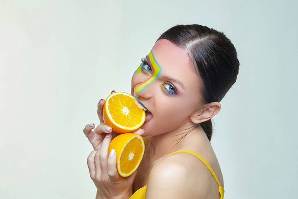 attractive young woman biting slice of orange - Valokuva, kuva