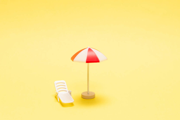 Két napozó és egy piros esernyő sárga háttérrel. Fénymásolási hely. - Fotó, kép