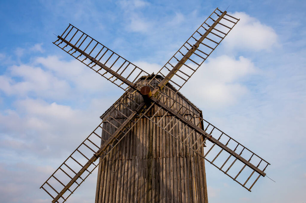 Molino de viento de madera en un museo rural al aire libre sobre el fondo del cielo azul. Condiciones de iluminación natural. - Foto, Imagen