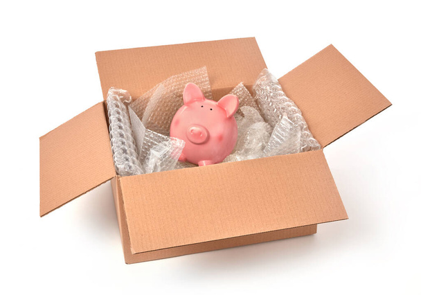 Свиная копилка, завернутая в пузырьки в картонную коробку - Фото, изображение