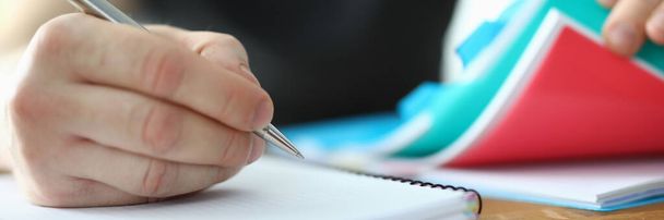 Man schrijven met pen in blanco pad en bladeren door map met documenten close-up. - Foto, afbeelding