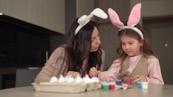 Boldog húsvétot! Egy vidám család készül a húsvéti ünnepre. Anya és lánya tojást festenek, festékkel játszanak. Otthon ülnek. - Felvétel, videó