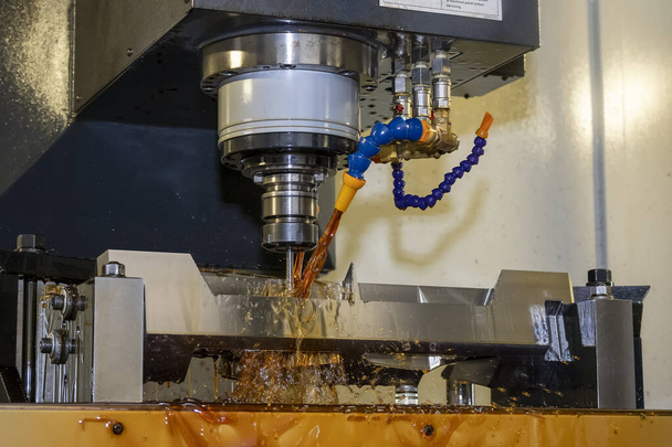A fresadora CNC cortando as peças do molde com o método de refrigeração a óleo. O processo de fabricação de moldes e matrizes pelo centro de usinagem CNC. - Foto, Imagem