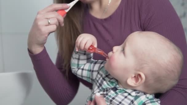 Maman apprend à se brosser les dents d'un petit enfant à la maison dans la salle de bain - Séquence, vidéo