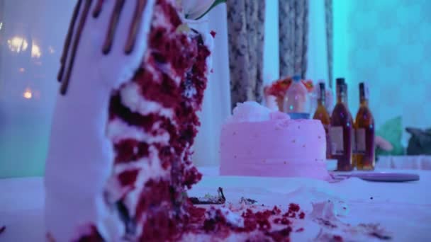 A születésnapi torta szeletelt szeletelt darabja néhány üveg ital hátterével szemben a fiatalok esti partiján fénysugarakban. - Felvétel, videó