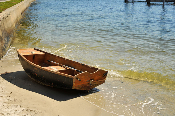 Pequeno veleiro amarrado contra uma praia
 - Foto, Imagem